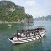 Garden Bay Cruise Bai Tu Long Bay gliding through peaceful emerald waters with local fishing boats and stunning natural scenery