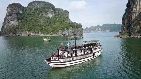 Garden Bay Cruise Bai Tu Long Bay gliding through peaceful emerald waters with local fishing boats and stunning natural scenery