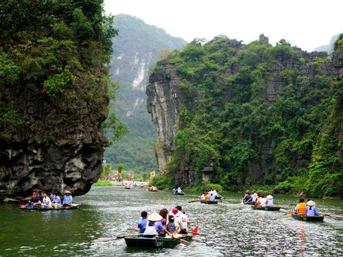 Visitors enjoy a boat trip through Trang An caves on the Full day Ninh Binh tour, surrounded by stunning karst scenery