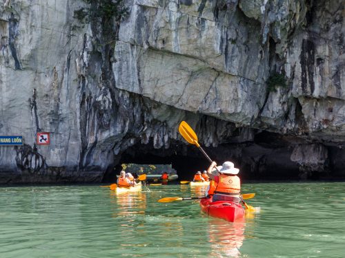 Tourists enjoying Hanoi Halong Bay day trip kayaking at Luon Cave in Ha Long Bay, Vietnam