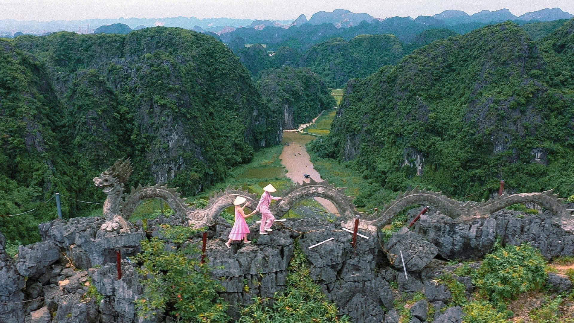 Ninh Binh Day Tour from Hanoi with a view from Mua Cave showing tourists walking beside the dragon statue and river scenery.