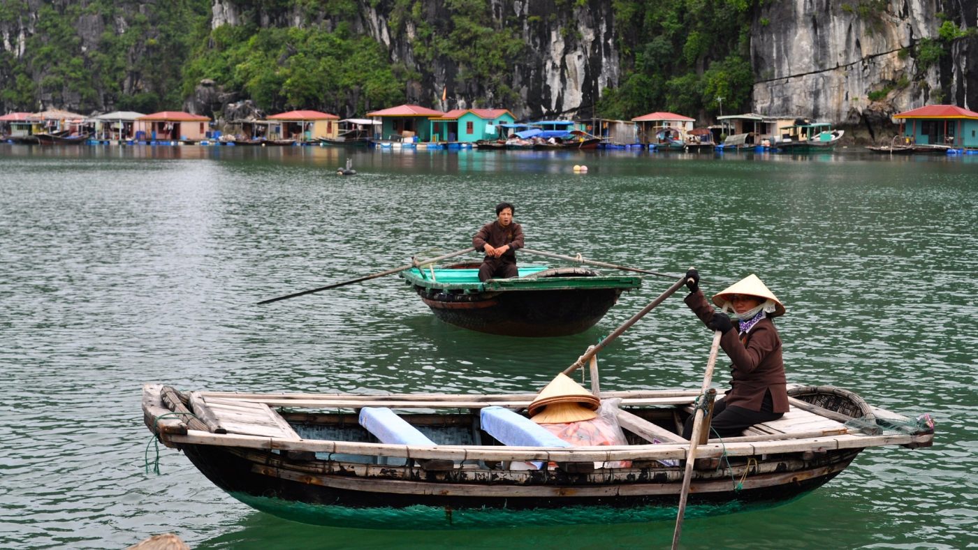 A picturesque scene of Vung Vieng Floating Fishing Village, featuring colorful floating houses and local fishermen in traditional boats, reflecting the unique lifestyle of the community