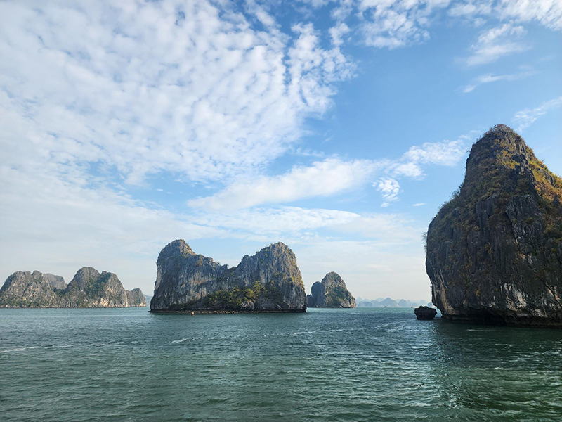 Limestone islands and tranquil waters of Bai Tu Long Bay under a clear blue sky